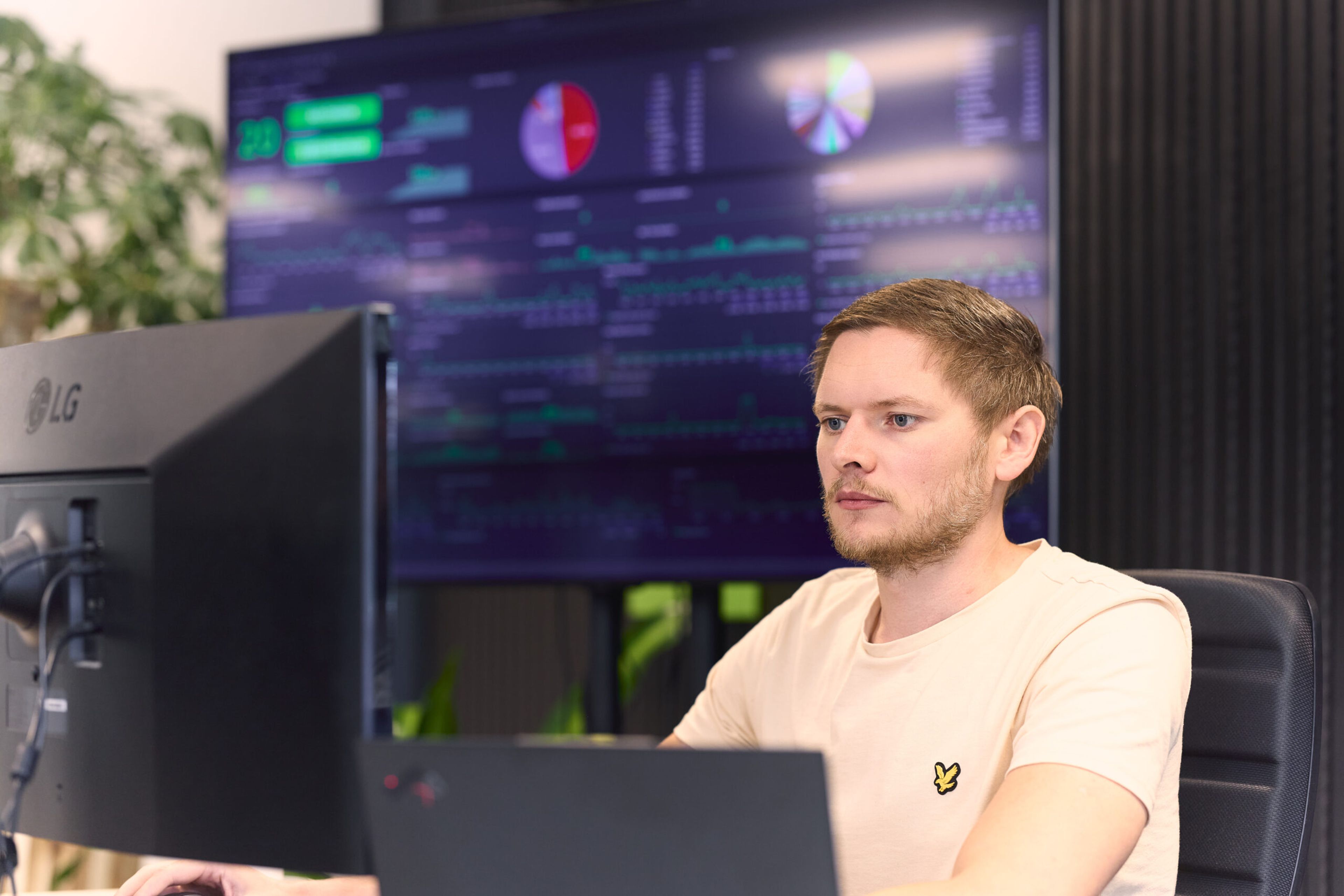 SQL Server specialist Marc kijkt naar zijn scherm, met op de achtergrond een groot scherm met dashboard